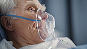 Man wearing oxygen mask in hospital bed