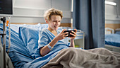 Boy using smartphone in hospital bed