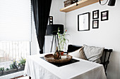 Table with white tablecloth, black bench and standard lamp in corner