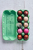 Colorful dyed Easter eggs in red tones in an egg carton