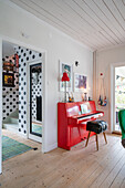 Red piano in living room and hallway with polka-dot wallpaper