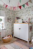 Old cupboard in vintage-style child's bedroom with floral wallpaper