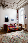 Colorful blanket on a sofa with wooden frame, coat hanger above with neon light