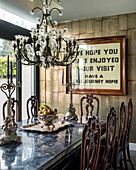 Chandelier above black marble table and baroque chairs