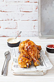 Roasted chicken drumsticks on newspaper sheet, ketchup and mayonnaise
