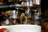 Close-up of double espresso dripping into cup