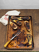 Gebratene Aubergine auf Backblech mit Geschirrtuch und Zweizinkengabel