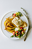 Oven baked sea bass, potato wedges and tomato salad