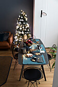 Laid Christmas table, in the background Christmas tree in front of a dark wall