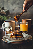 Gestapelte Pancakes mit Honig beträufeln