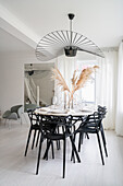 Bright dining area with black chairs, above designer lamp in front of window