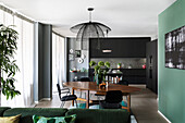 Open plan living room with black fitted kitchen cabinets, dining area, and green sofa