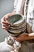 Frau hält einen Stapel leere Keramikschalen