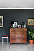 Old wooden chest of drawers in front of a black wall in the room