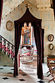 Burgundy curtains, wrought iron staircase, Roman plaster cameos and foil wallpaper in hallway