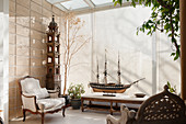 Model ship and armchair in conservatory with blinds