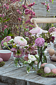 Easter table decoration with ranunculus and spring roses, Easter eggs on moss