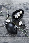 Black decorative egg with quail eggs and feathers