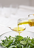 Olivenöl auf Löffel über grünem Salat