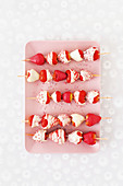 Colorful strawberry skewers with candy icing and sugar pearls