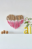 Love heart made from pink-painted twigs, yellow decorative letters and vase