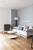 White sofa, armchair and round coffee table in grey-and-white living room