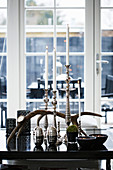 Silver candlesticks with white candles and antlers on black table