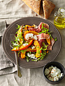 Salad with baked pumpkin, prosciutto and goat cheese