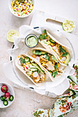 Fish tacos and radish sweet pepper salsa served ith guacamole on bright surface