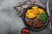 Grilled beef steak with potato wedges and peas