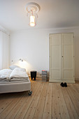 Bed on castors in room with pale board floor