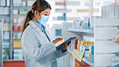 Pharmacist wearing a face mask using a tablet