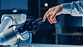 Robotic arm touching a human hand
