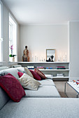 Pale sofa with scatter cushions in front of candles and head of Shiva on shelves