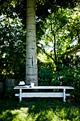 Weißer Holztisch unter einem Baum im Garten
