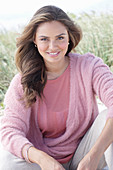 A young, long-haired woman wearing a pink blouse and a pink wrap-around jumper