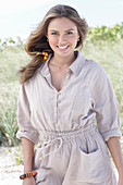 A young, long-haired woman wearing a beige linen blouse and shorts