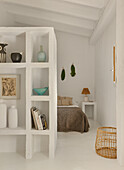 White shelf as room divider, with a sleeping area in the background
