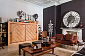 Large clockface on marble fireplace in drawing room with a metal sculpture figure, books, candelabra and minaret finials are arranged on top of an marquetry cabinet