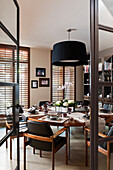 Glass and metal doors lead through to a formal dining room with laid table
