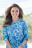 A young woman with long hair wearing a blue patterned dress