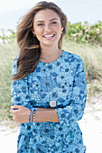 A young woman with long hair wearing a blue patterned dress