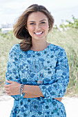 A young woman with long hair wearing a blue patterned dress