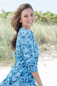 A young woman with long hair wearing a blue patterned dress