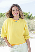 A young woman with long hair wearing a yellow jumper