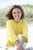 A young woman with long hair wearing a yellow jumper and trousers