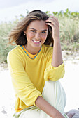 A young woman with long hair wearing a yellow jumper and trousers