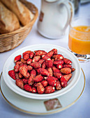 Wilde Erdbeeren in einem Schälchen auf Frühstückstisch