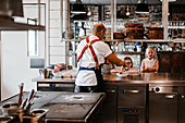 Girls watching chef working in restaurant kitchen