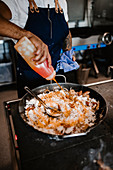 Koch bereitet Paella zu